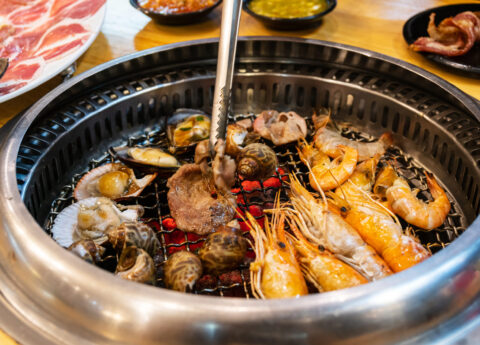 Young asian woman eating seafood yakiniku japanese grilled